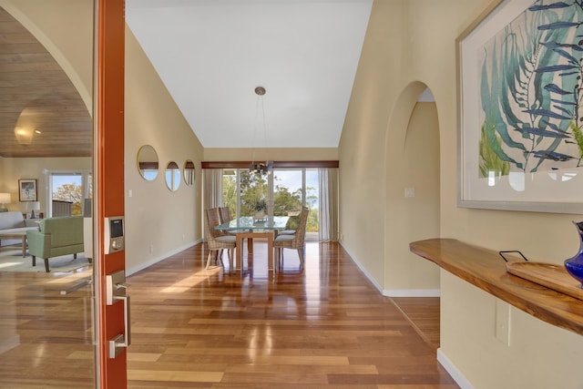 dining area with baseboards, high vaulted ceiling, and wood finished floors