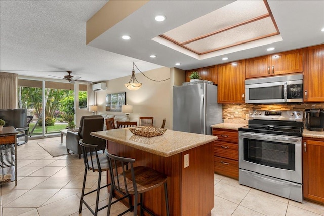 kitchen featuring ceiling fan, stainless steel appliances, backsplash, a wall mounted AC, and a kitchen island