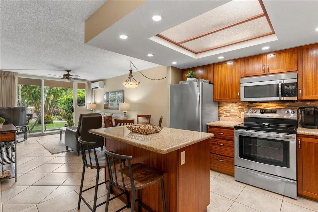 2575 S Kihei Rd Unit G105, Kihei, HI 96753 - kitchen with appliances with stainless steel finishes, a wall mounted air conditioner, open floor plan, brown cabinetry, and backsplash