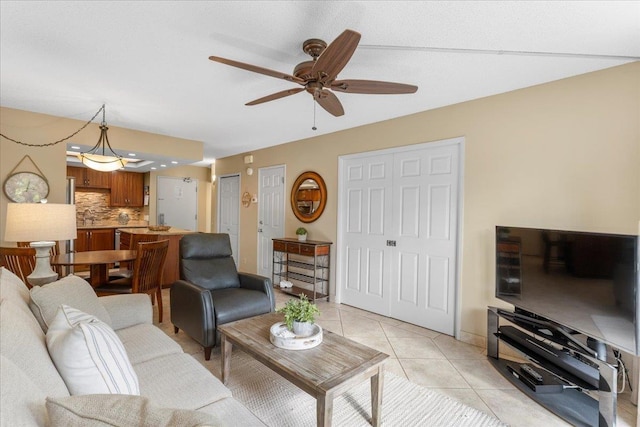 tiled living room featuring ceiling fan and sink