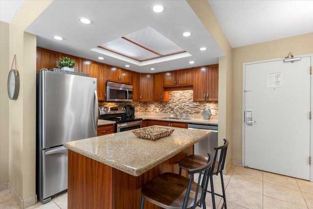 kitchen with a breakfast bar, a center island, sink, decorative backsplash, and appliances with stainless steel finishes