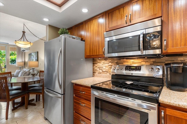 kitchen featuring tasteful backsplash, light stone counters, stainless steel appliances, decorative light fixtures, and light tile patterned flooring