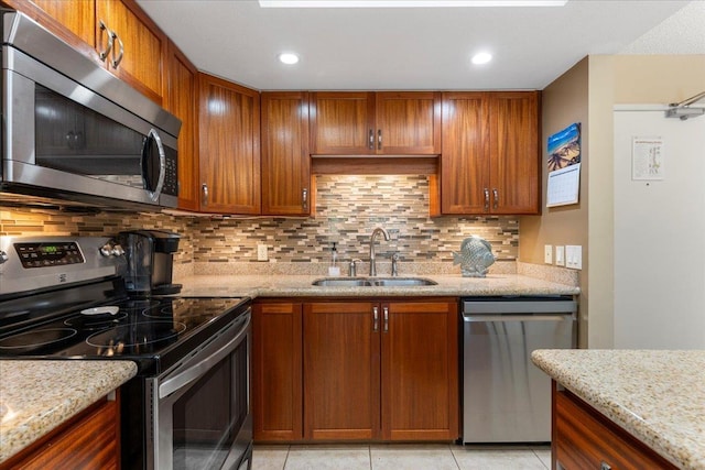 kitchen with tasteful backsplash, light stone counters, sink, and appliances with stainless steel finishes