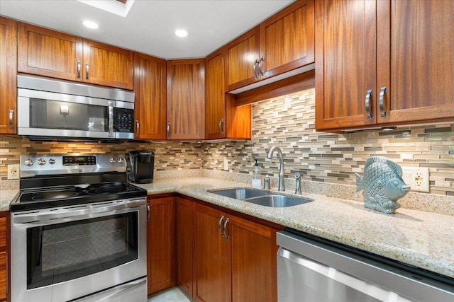 kitchen with light stone countertops, stainless steel appliances, tasteful backsplash, and sink