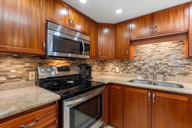 kitchen with decorative backsplash, sink, stainless steel appliances, and light stone counters