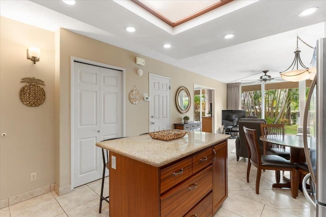 kitchen featuring ceiling fan, a kitchen island, light tile patterned floors, and a textured ceiling