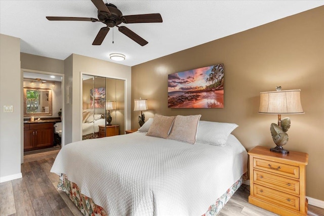 bedroom with hardwood / wood-style floors, ceiling fan, ensuite bath, and a closet