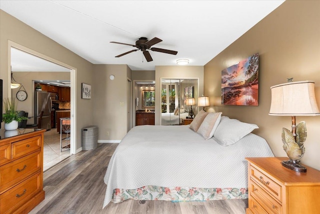 bedroom with ensuite bath, ceiling fan, dark hardwood / wood-style flooring, stainless steel fridge, and a closet