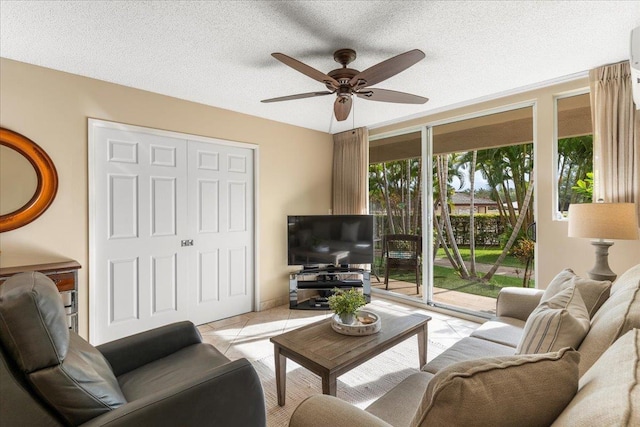 tiled living room featuring ceiling fan, a textured ceiling, and a wealth of natural light