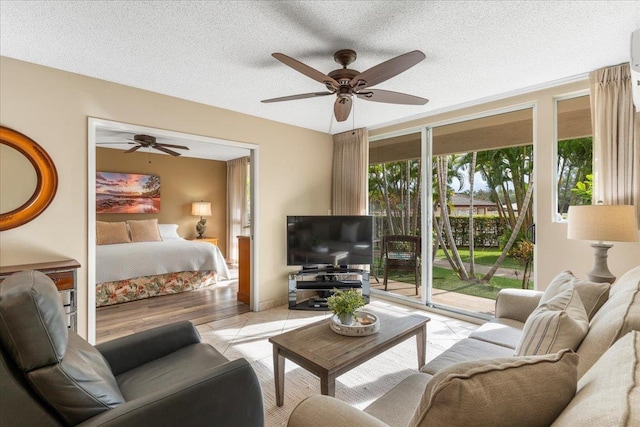 living room featuring ceiling fan, light hardwood / wood-style floors, a textured ceiling, and a wealth of natural light