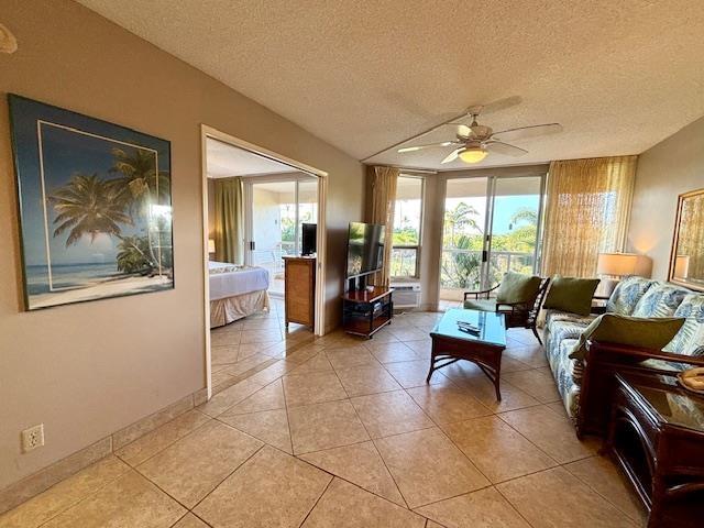 living area with ceiling fan, a textured ceiling, and light tile patterned floors