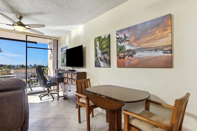 tiled dining area with ceiling fan, a wall of windows, and a textured ceiling