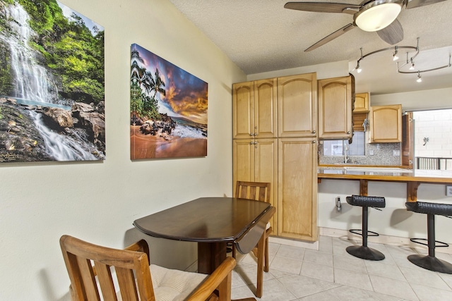 tiled dining space with a textured ceiling and ceiling fan