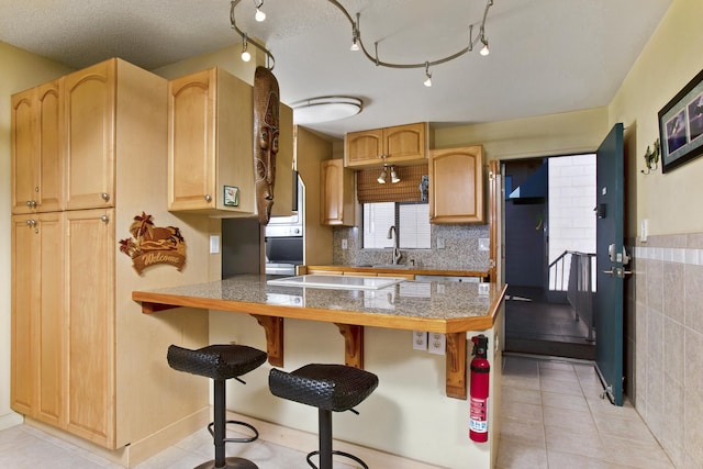 kitchen featuring a breakfast bar, light brown cabinets, kitchen peninsula, and electric stovetop