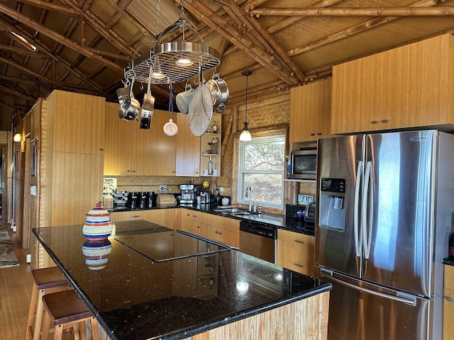 kitchen with a sink, dark stone counters, a center island, and appliances with stainless steel finishes