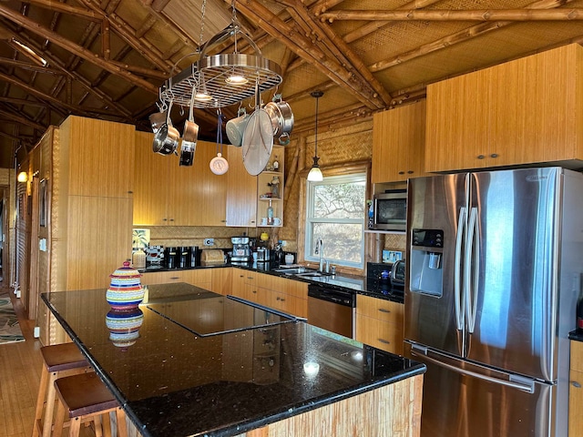 kitchen with a center island, hardwood / wood-style floors, stainless steel appliances, sink, and dark stone counters