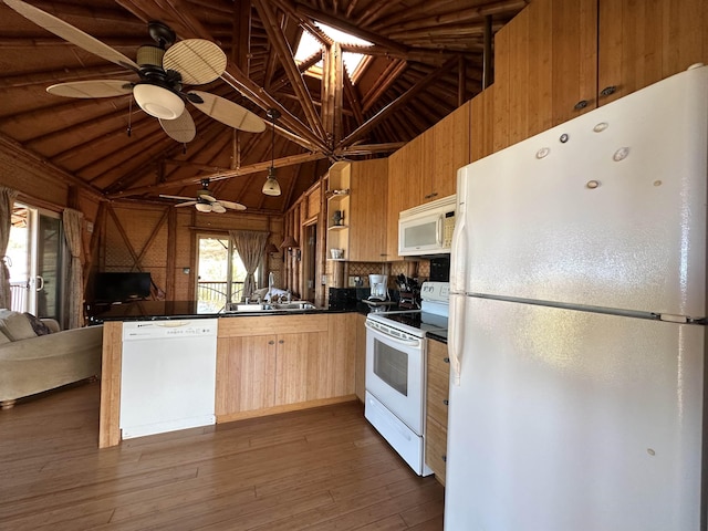 kitchen with vaulted ceiling, a sink, dark countertops, and white appliances