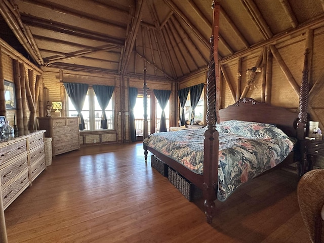 bedroom featuring access to exterior, lofted ceiling with beams, and wood finished floors