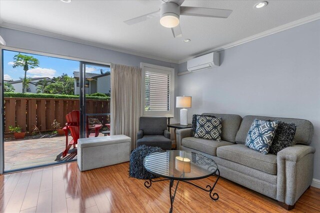 living room featuring a wall mounted air conditioner, wood-type flooring, ceiling fan, and crown molding