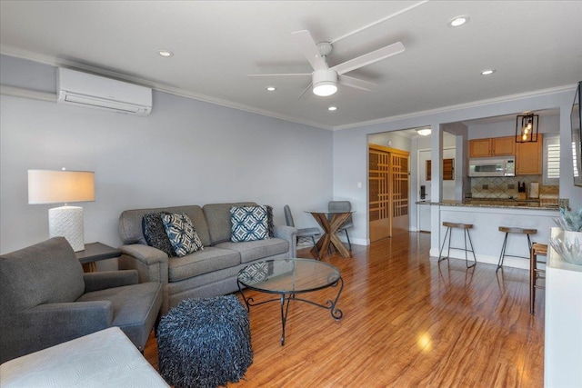 living room featuring a wall mounted air conditioner, light hardwood / wood-style flooring, ceiling fan, and ornamental molding