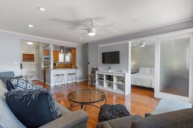 living room featuring ceiling fan, light wood-type flooring, and crown molding