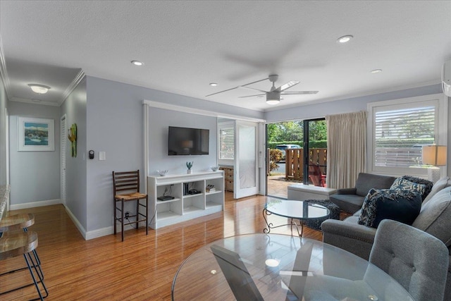 living room featuring a textured ceiling, light wood-type flooring, ceiling fan, and crown molding