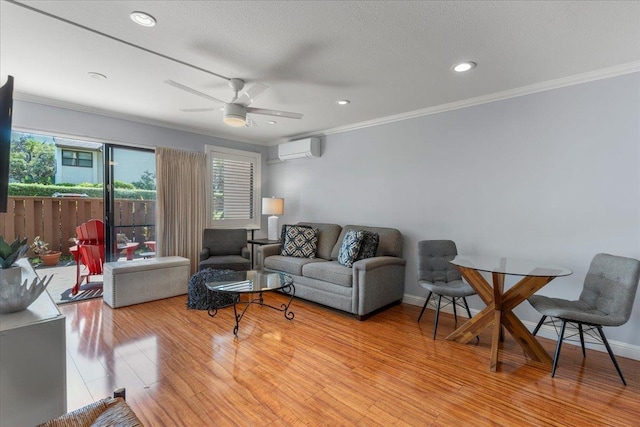living room featuring a wall unit AC, ceiling fan, plenty of natural light, and light hardwood / wood-style floors