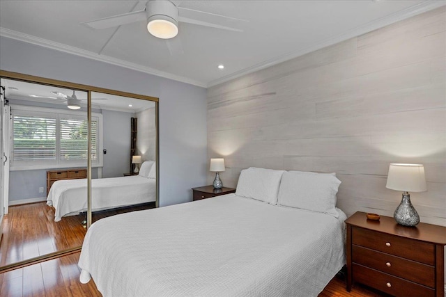 bedroom featuring hardwood / wood-style flooring, ceiling fan, ornamental molding, and a closet