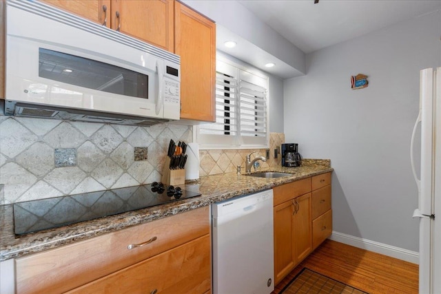 kitchen with white appliances, stone counters, sink, decorative backsplash, and dark hardwood / wood-style floors