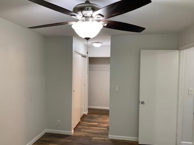 unfurnished bedroom with ceiling fan, dark wood-type flooring, and a closet