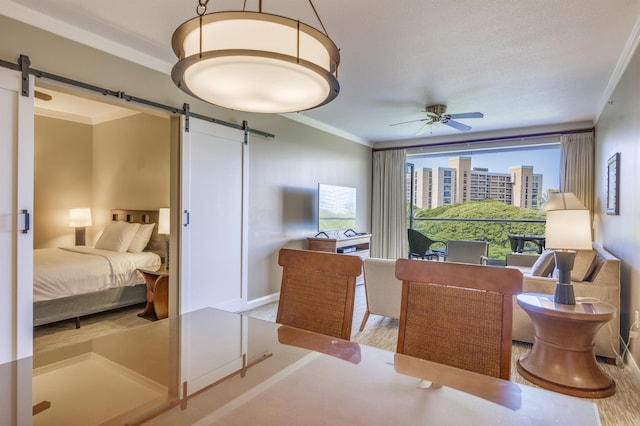 bedroom with light hardwood / wood-style floors, crown molding, a barn door, and ceiling fan