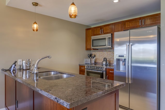 kitchen with sink, stone counters, stainless steel appliances, hanging light fixtures, and decorative backsplash