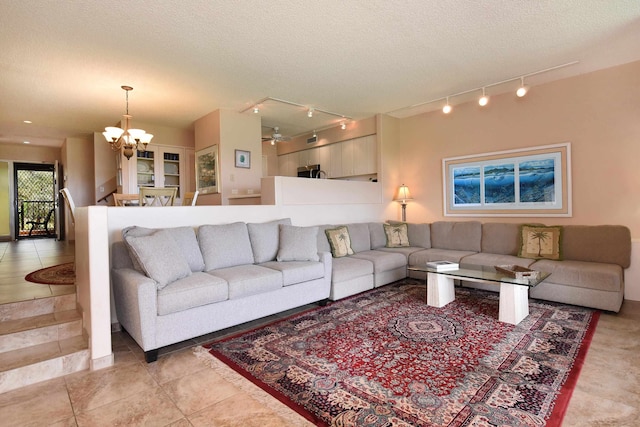 living room with light tile floors, track lighting, a textured ceiling, and ceiling fan with notable chandelier