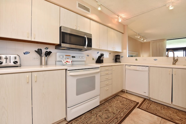 kitchen featuring white appliances, sink, light tile floors, rail lighting, and tasteful backsplash