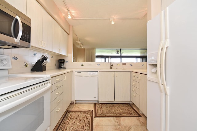 kitchen with backsplash, white appliances, track lighting, sink, and light tile floors