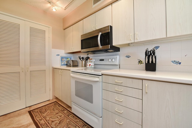 kitchen with light tile flooring, white electric range oven, track lighting, tasteful backsplash, and a textured ceiling