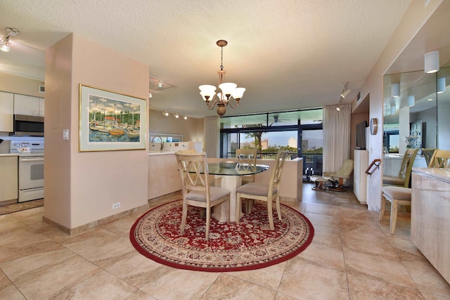 dining area with a notable chandelier, a textured ceiling, light tile flooring, and rail lighting