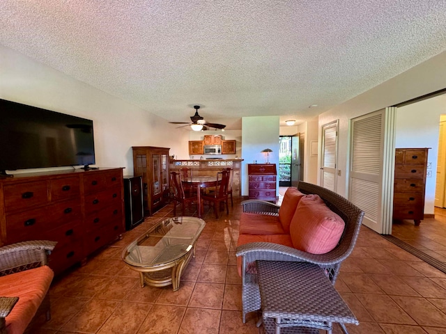 living room featuring tile patterned floors, ceiling fan, and a textured ceiling