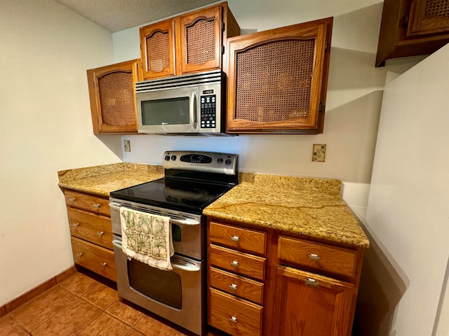 kitchen featuring light stone counters, light tile patterned floors, and stainless steel appliances