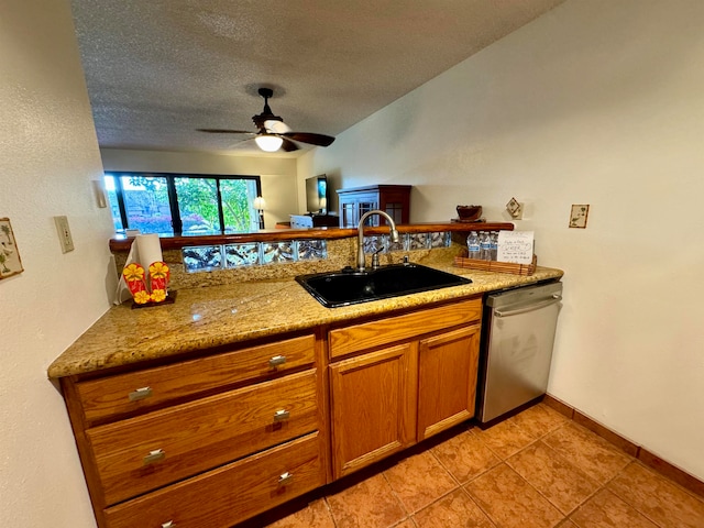 kitchen featuring light stone countertops, stainless steel dishwasher, a textured ceiling, ceiling fan, and sink