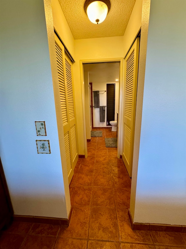 hall with tile patterned floors and a textured ceiling