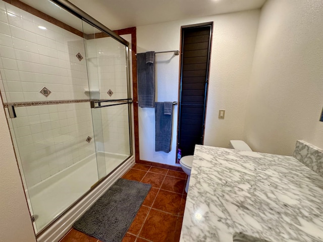 bathroom with tile patterned flooring, vanity, toilet, and an enclosed shower