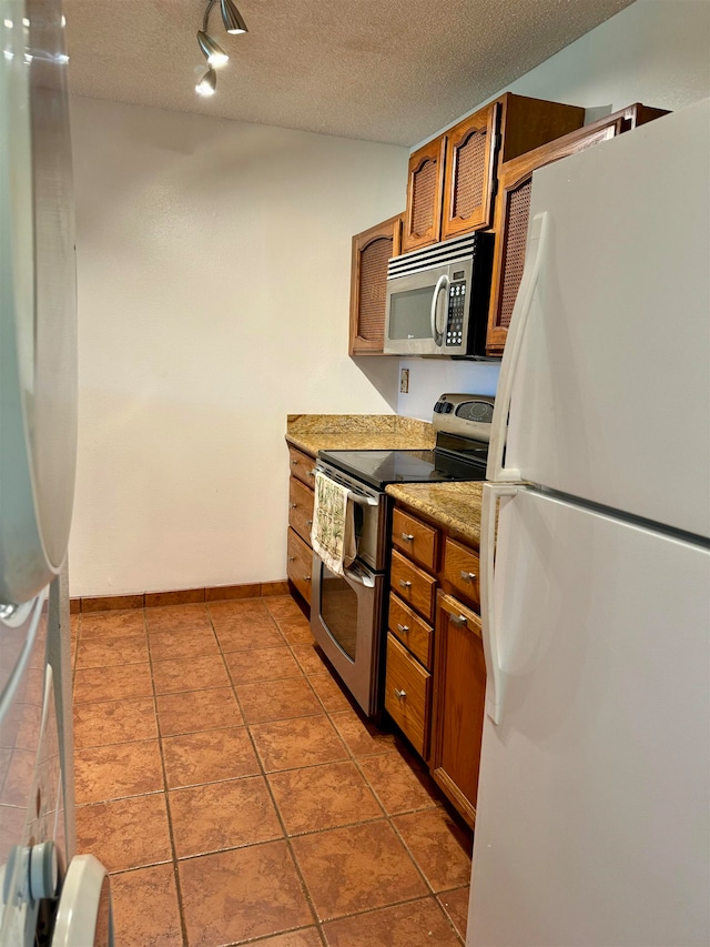 kitchen featuring appliances with stainless steel finishes, a textured ceiling, track lighting, and tile patterned floors