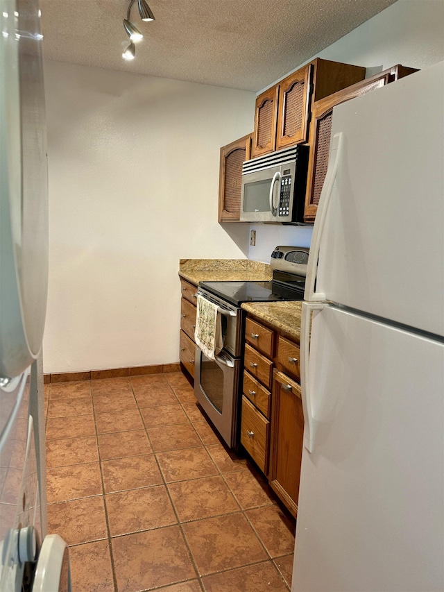 50 Kepuhi Pl Unit 103, Maunaloa, HI 96770 - kitchen with stainless steel appliances, brown cabinets, a textured ceiling, and tile patterned floors