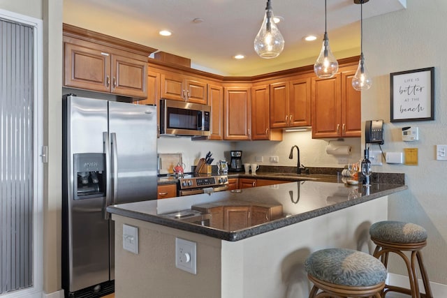 kitchen featuring sink, hanging light fixtures, a kitchen bar, kitchen peninsula, and stainless steel appliances