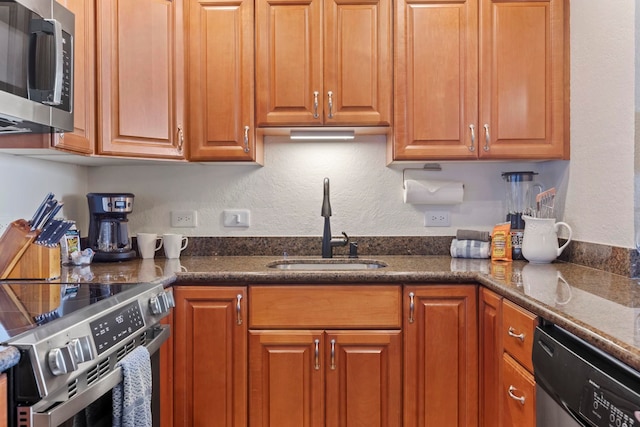 kitchen with dark stone countertops, sink, and appliances with stainless steel finishes