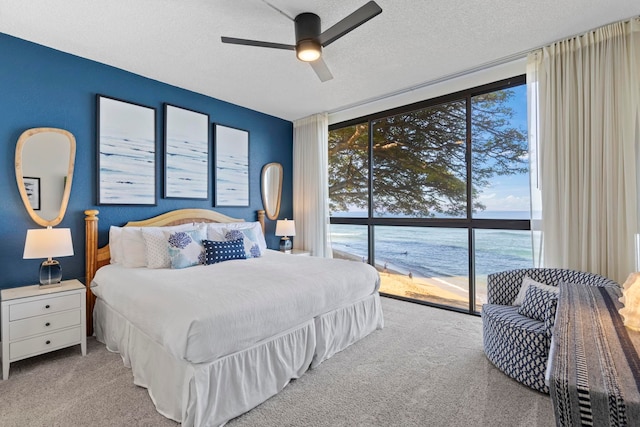 carpeted bedroom with a textured ceiling, a water view, and ceiling fan