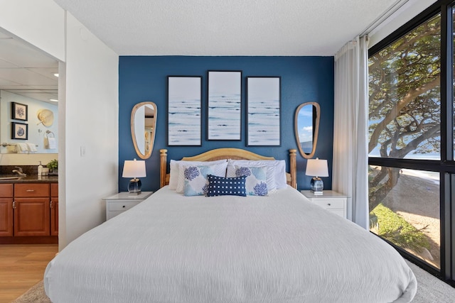 bedroom featuring sink, light hardwood / wood-style floors, and a textured ceiling