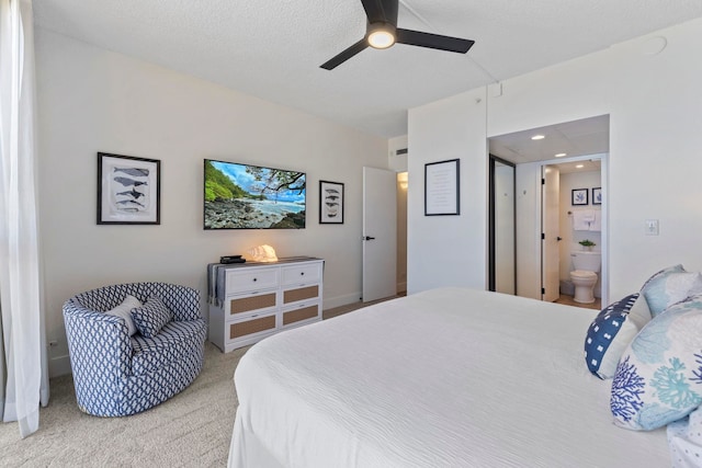 bedroom with a textured ceiling, carpet floors, ensuite bathroom, and ceiling fan