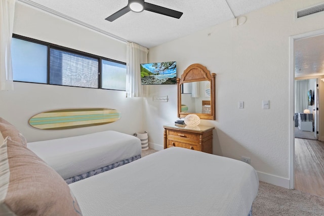 bedroom with wood-type flooring, a textured ceiling, and ceiling fan